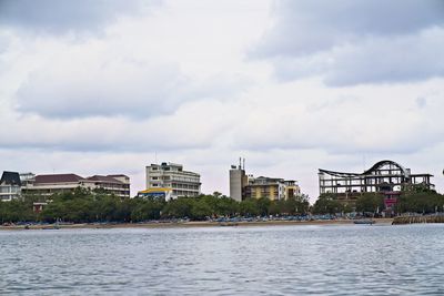 Sea by buildings against sky in city