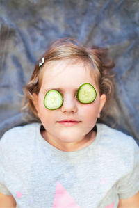 High angle view of girl with cucumber slices on eyes in spa