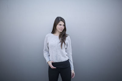 Portrait of young woman standing against white background