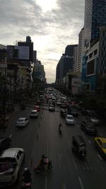 Vehicles on road amidst buildings in city against sky