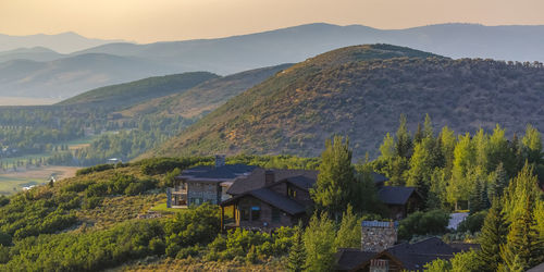 Scenic view of trees and houses by mountains against sky