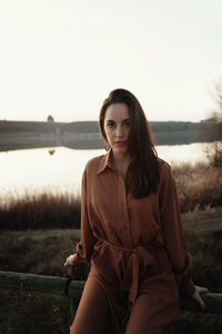 Portrait of young woman sitting against sky