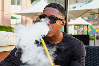 Portrait of young man smoking cigarette outdoors