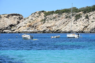 Sailboats in sea against clear blue sky