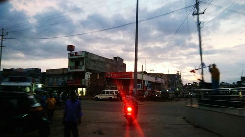 Cars on street in city against sky at dusk