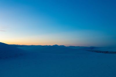 Scenic view of snowcapped mountains against clear blue sky during sunset