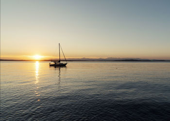 Sailboat in sea against sky during sunset