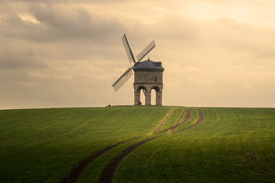 Traditional windmill on field against sky