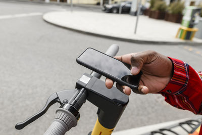 Man with push scooter using smart phone on street