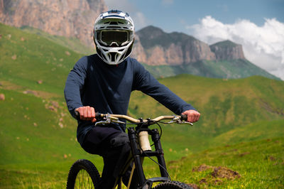 Male athlete cyclist in helmet and protective mask outdoors. mtb rider in mountainous terrain