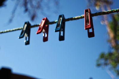 Low angle view of clothespins hanging on clothesline against sky