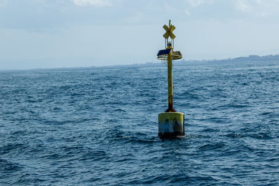 Lighthouse by sea against sky