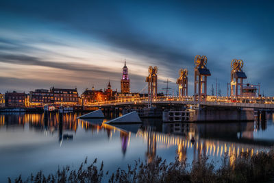 View of illuminated bridge and buildings in city against sky during dusk