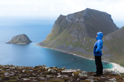 Side view of woman looking at sea from mountain against sky