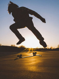 Man in mid-air skateboarding against sky during sunset