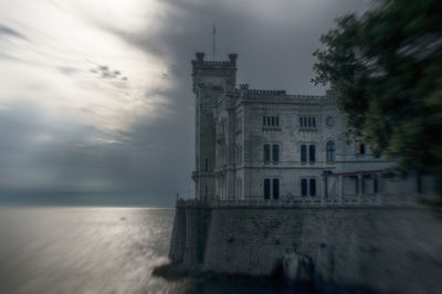 Building by sea against sky at dusk
