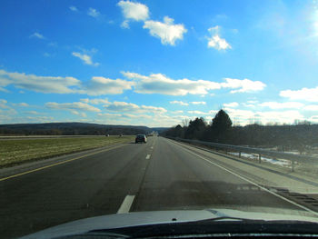 Road seen through car windshield against sky