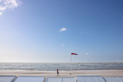 Man standing by windsock at beach against sky