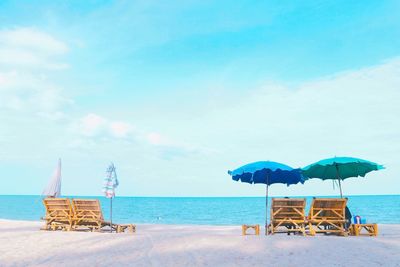 Deck chairs at beach against sky