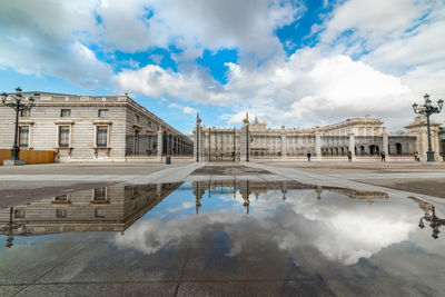 Reflection of historical building in puddle against sky