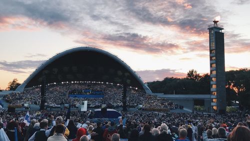 People at music concert against sky during sunset