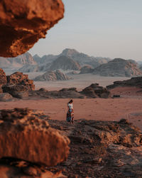 People on rock by mountains against sky