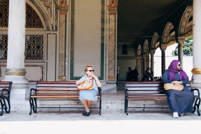 Full length of woman sitting on railing