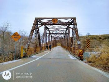 Road sign on bridge against sky