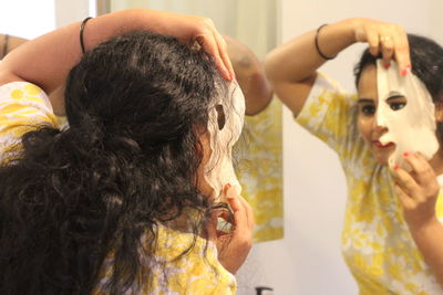 Rear view of woman removing facial mask