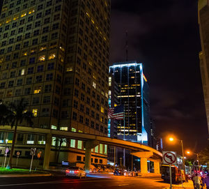 Illuminated buildings by street in city at night