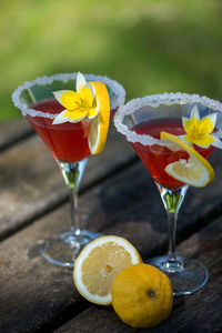 High angle view of drink garnished with yellow flower with lemon slice on wooden table