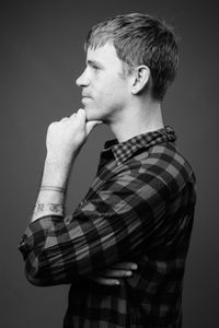 Side view of young man looking away against gray background