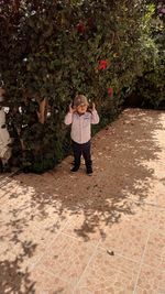 Boy standing on footpath by trees 