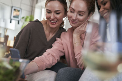 Portrait of friends sitting on sofa at home