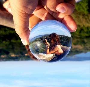 Midsection of person holding crystal ball with reflection