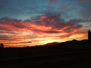 Silhouette landscape against dramatic sky during sunset