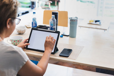 Midsection of woman using laptop on table