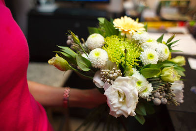 Midsection of woman holding bouquet outdoors