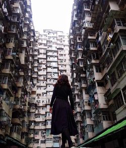 Rear view of woman standing amidst buildings