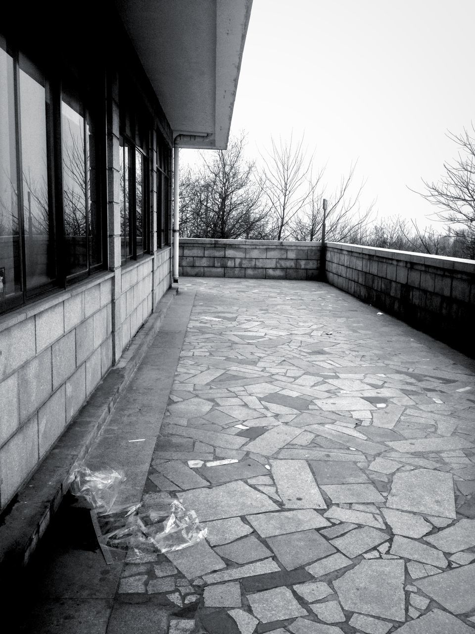 built structure, architecture, the way forward, clear sky, building exterior, diminishing perspective, empty, day, walkway, no people, railing, outdoors, sky, footpath, vanishing point, connection, sunlight, wall - building feature, cobblestone, long