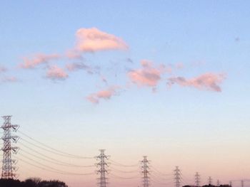 Low angle view of electricity pylon against sky at sunset