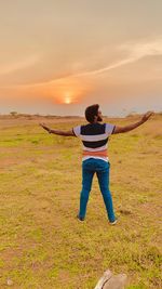 Full length of man standing on field against sky during sunset