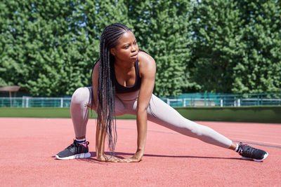 African american coach shows effective exercise for warming up before workout on hot summer day