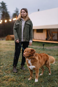 Young woman with dog standing outdoors