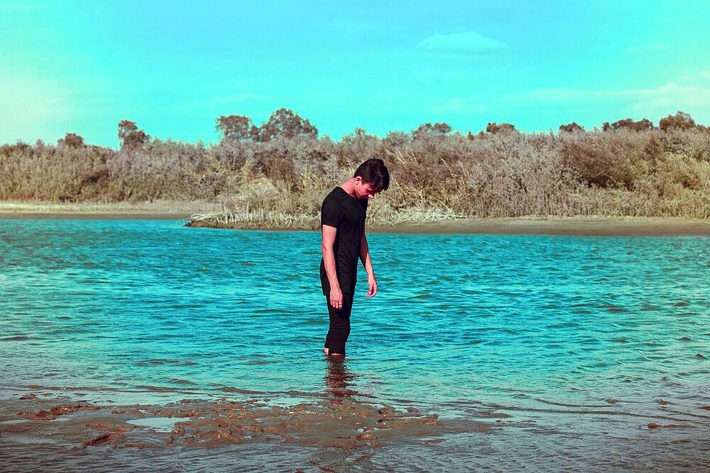 water, sea, lifestyles, tranquil scene, full length, tranquility, blue, standing, leisure activity, rear view, scenics, beauty in nature, sky, beach, nature, person, casual clothing, idyllic