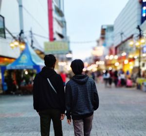 Rear view of people walking on street in city