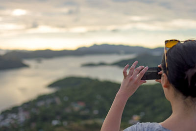 Woman photographing against sky