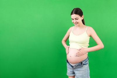 Smiling young woman standing against green background