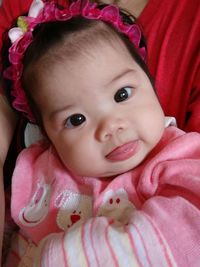 Portrait of cute baby girl lying on bed