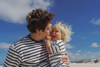 Portrait of young man with his son standing against sky